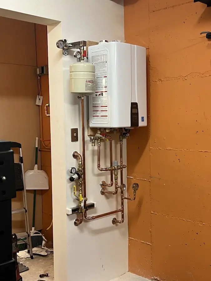 Plumbing technician inspecting water heater connections in Lowesville